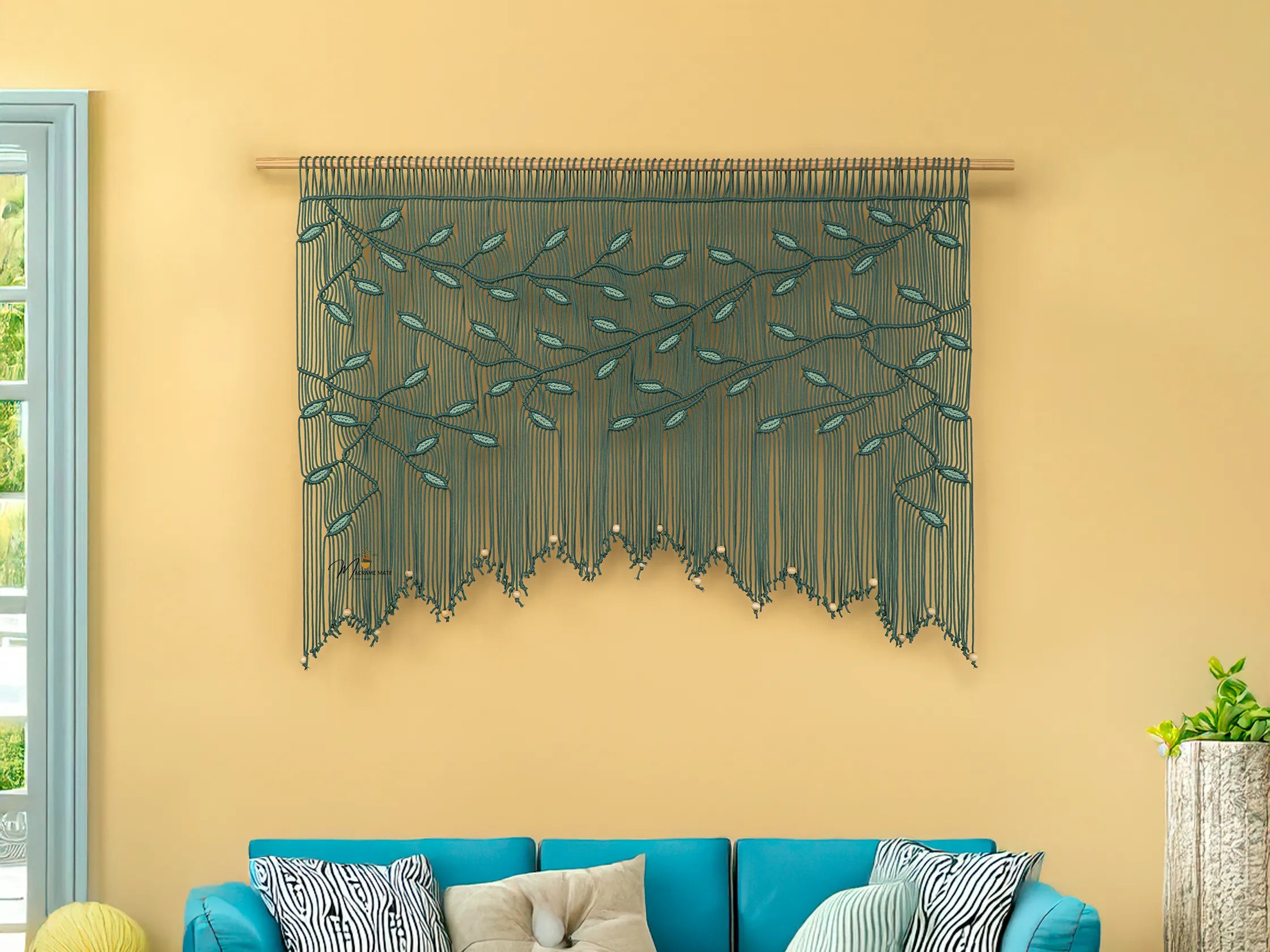 Decorative string art on a yellow wall above a blue sofa with patterned cushions.
