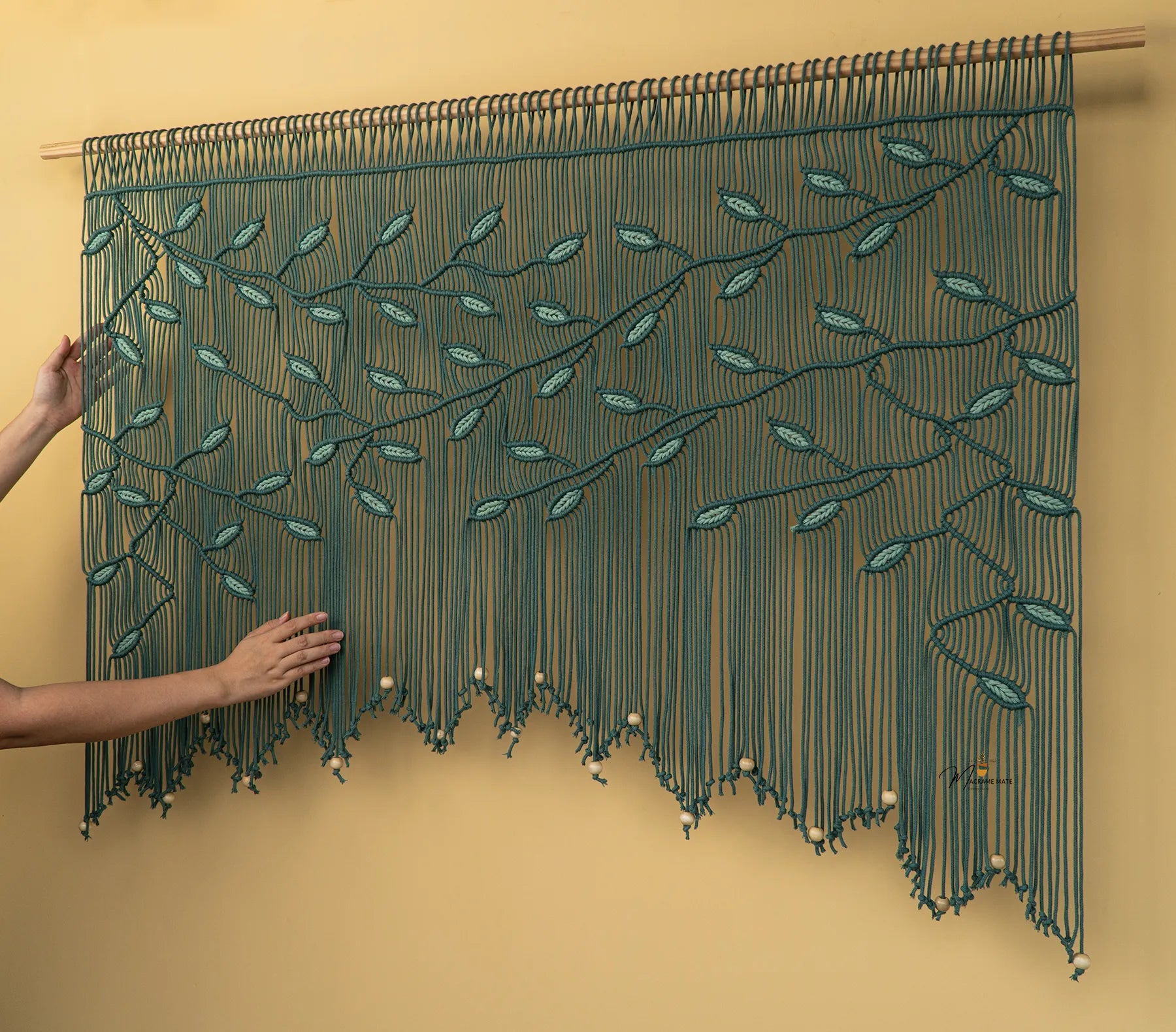 Textile art piece with leaf patterns on a beige background