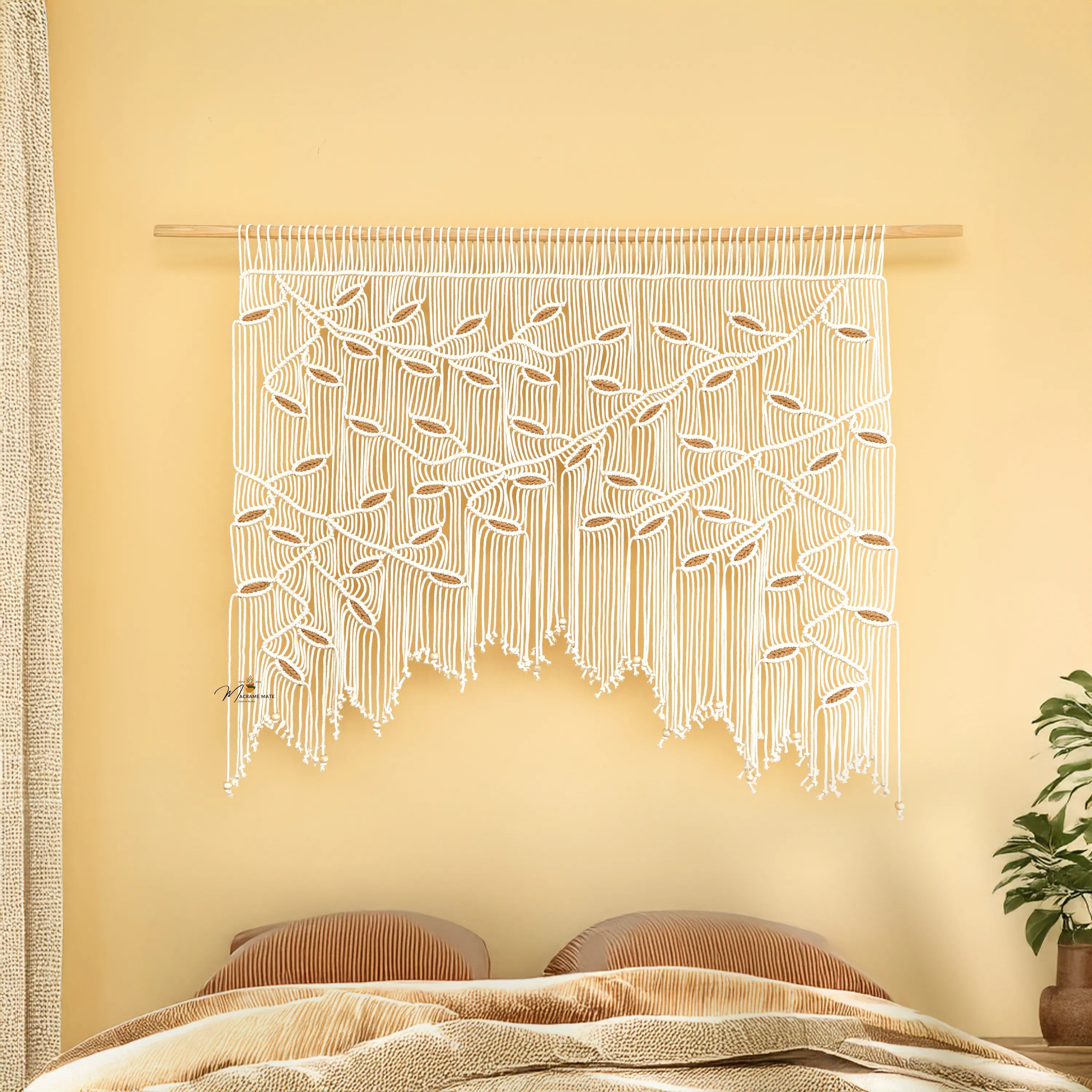 Macrame wall hanging with leaf pattern on a yellow wall above a bed.
