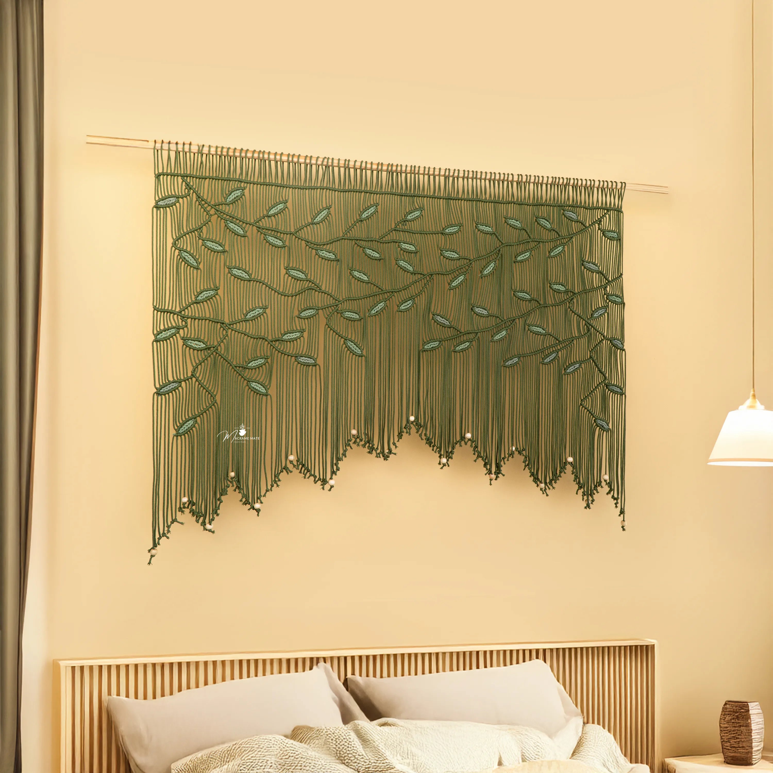Decorative string art with green leaves on a beige wall above a bed.