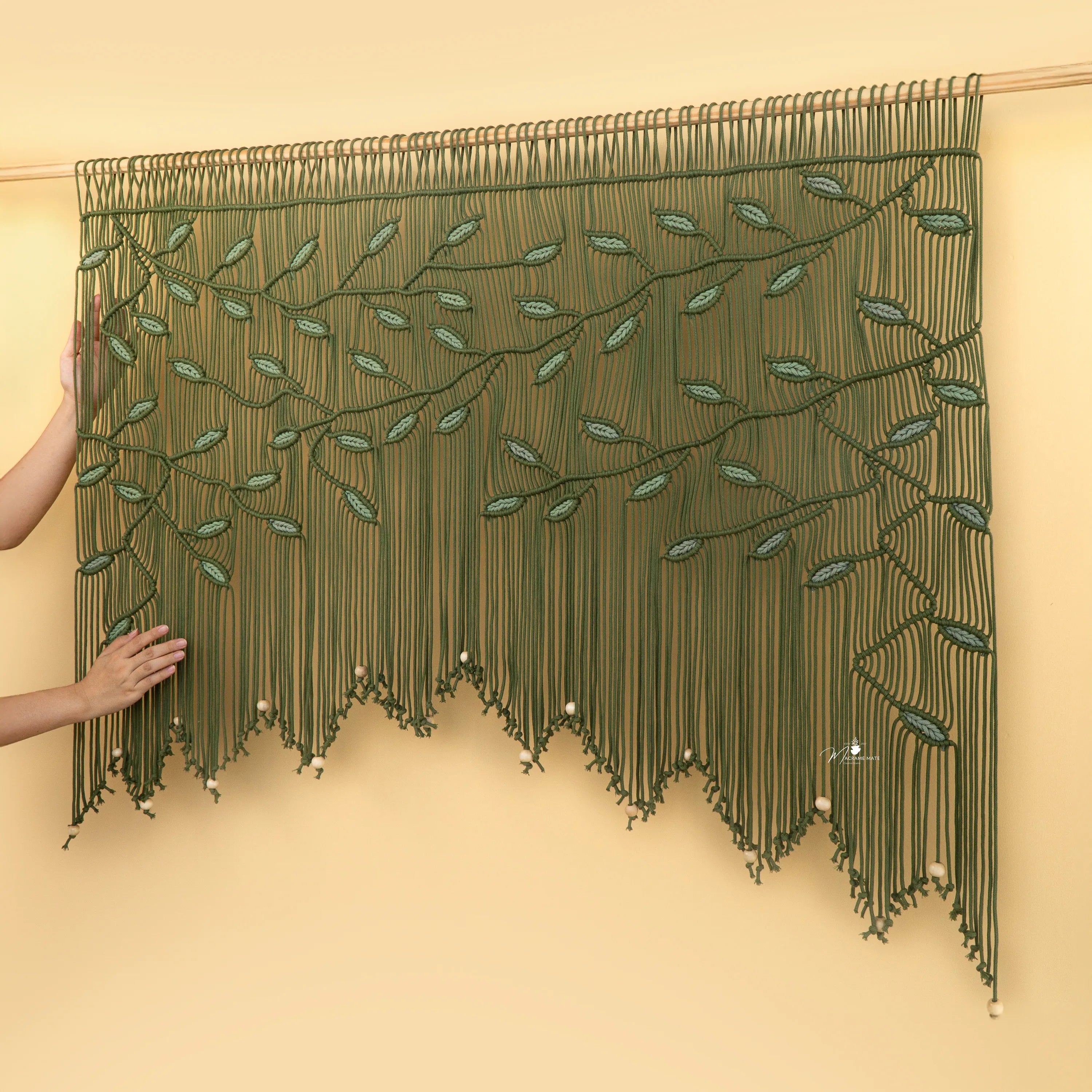 Green beaded curtain with leaf patterns on a beige wall