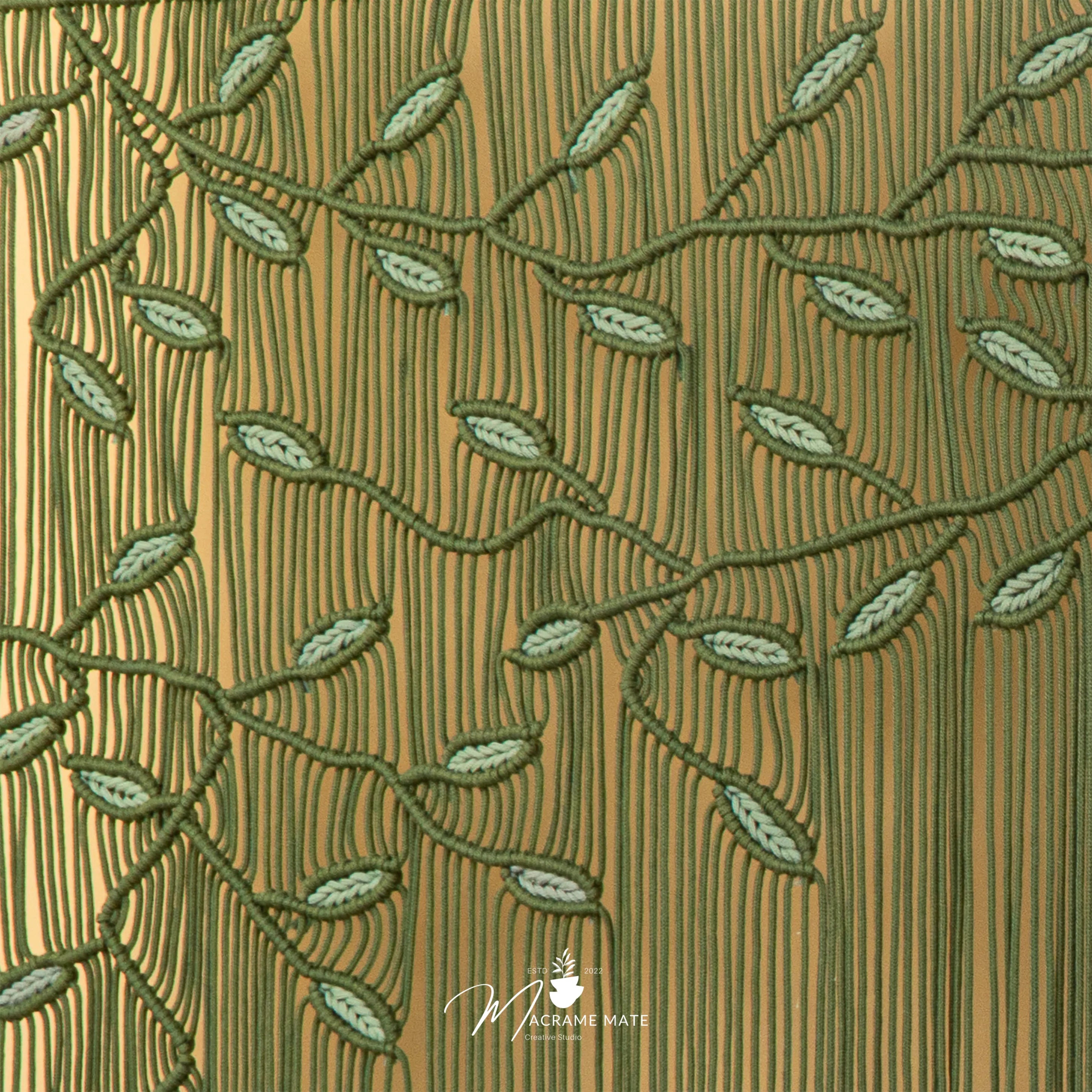 Textured fabric with embroidered green leaves on a brown background, featuring the brand 'Magazine Mate'.