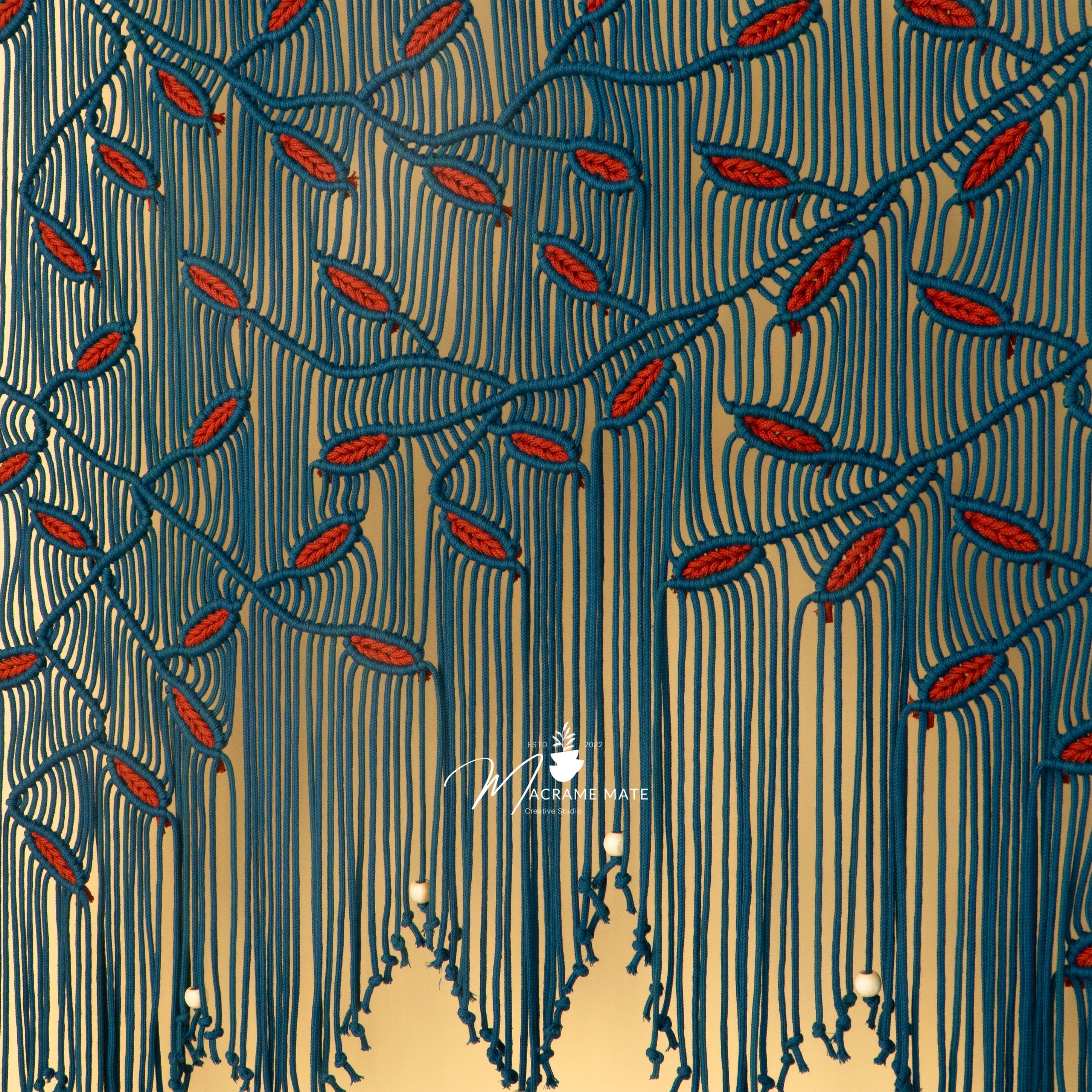 Decorative pattern with red leaves and blue stems on a beige background, featuring a brand logo.