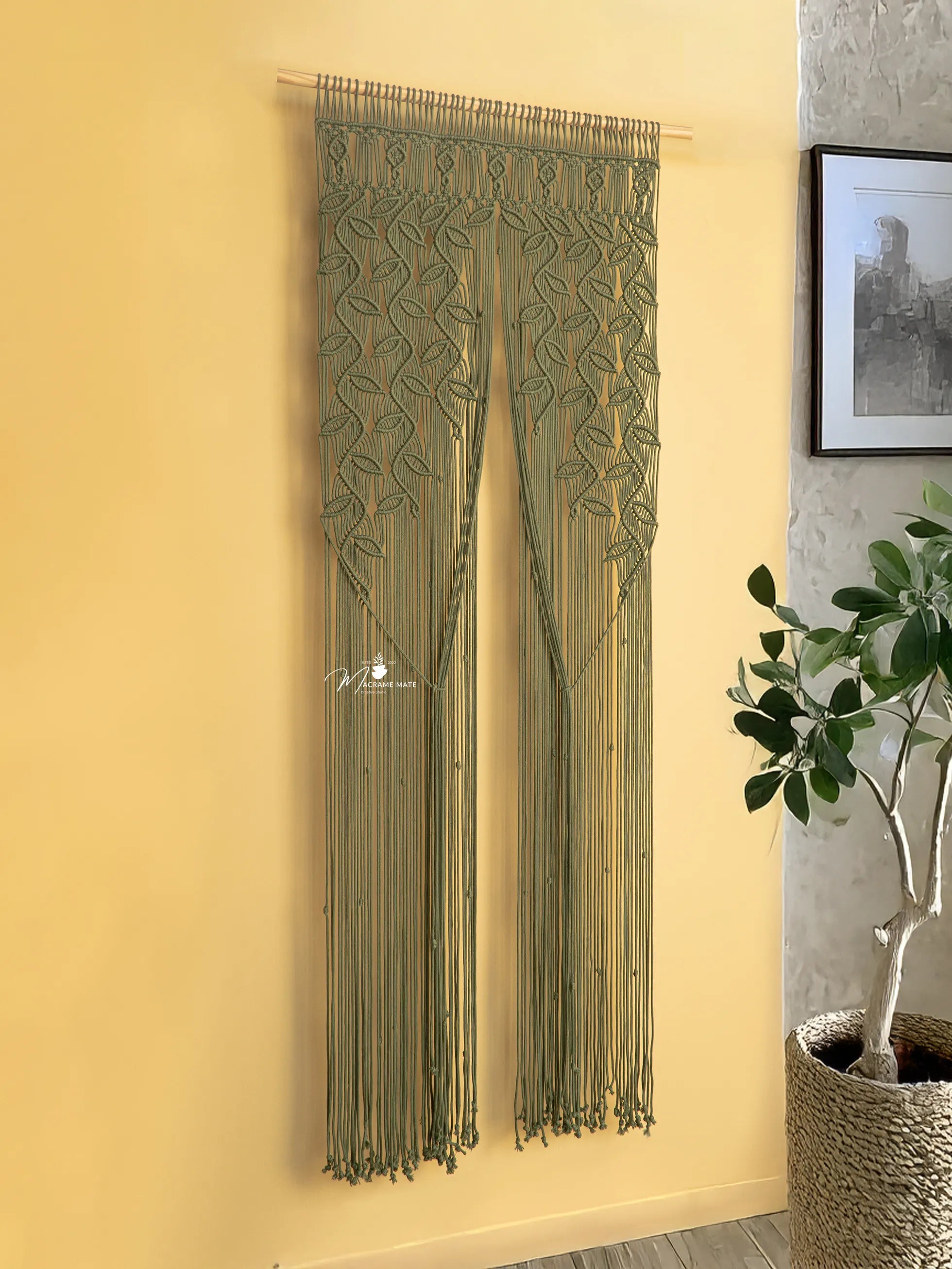 Decorative string curtain hanging on a yellow wall with a plant and framed picture in the background.