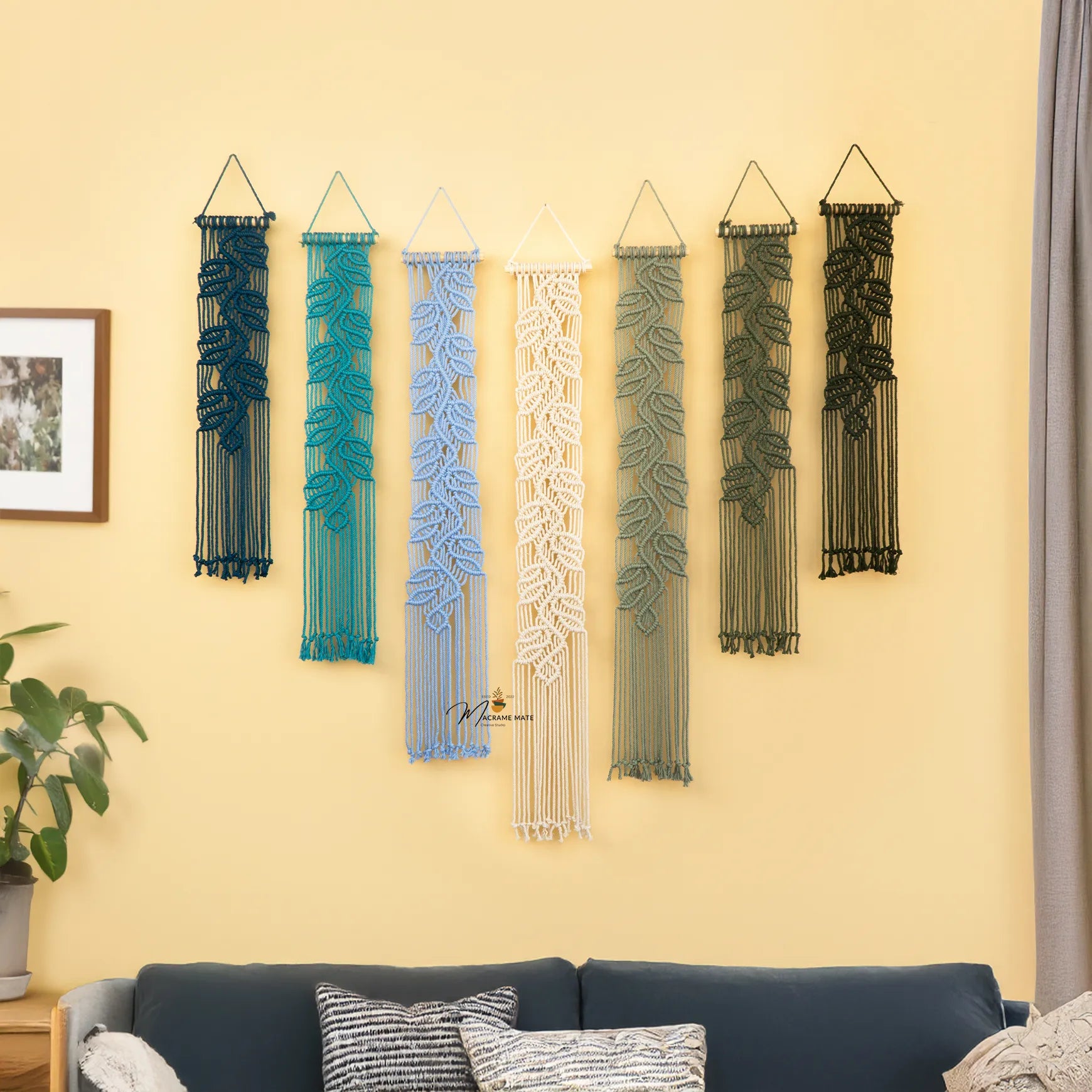Decorative wall hangings in various colors on a yellow wall above a sofa.
