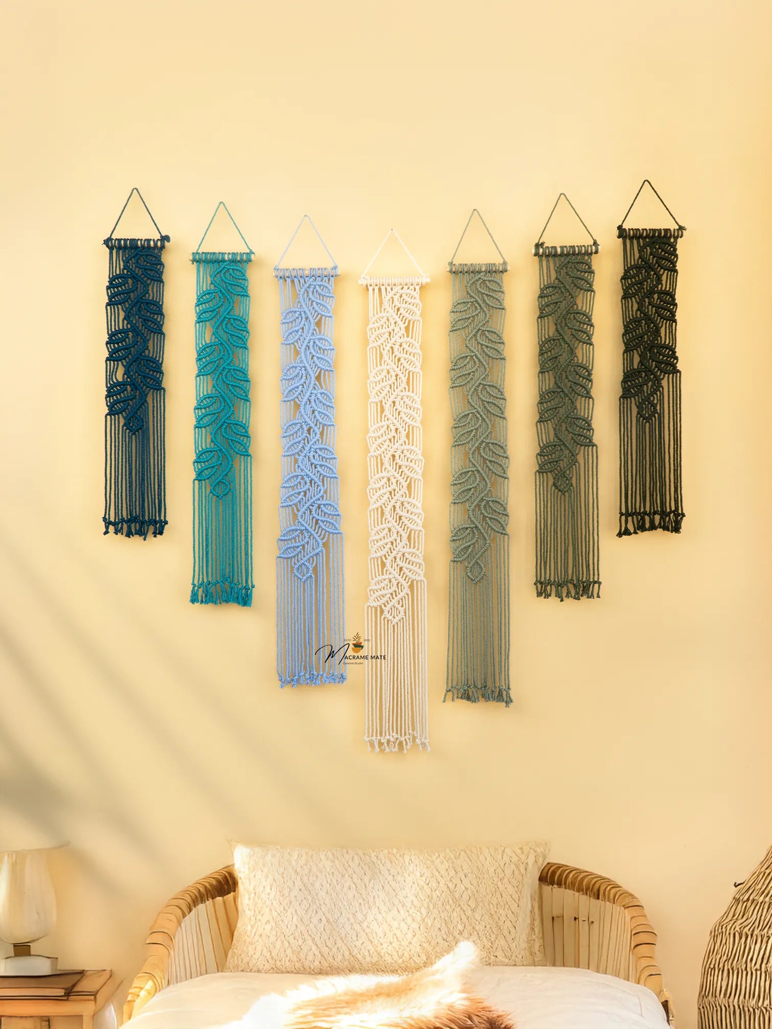 Set of six string art wall decorations on a yellow wall with a wicker chair and lamp in the foreground.