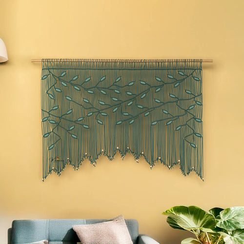 Decorative string art with leaf pattern on a yellow wall above a sofa.