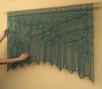 Textile art piece with leaf patterns on a beige background