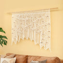 Macrame wall hanging on a yellow wall with a brown couch and green plant