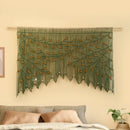 Decorative wall hanging with green leaves on a beige wall above a sofa.