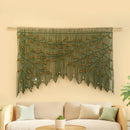 Decorative wall hanging with leaf pattern above a beige sofa on a light yellow wall.