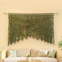 Decorative wall hanging with leaf pattern above a beige sofa on a light yellow wall.