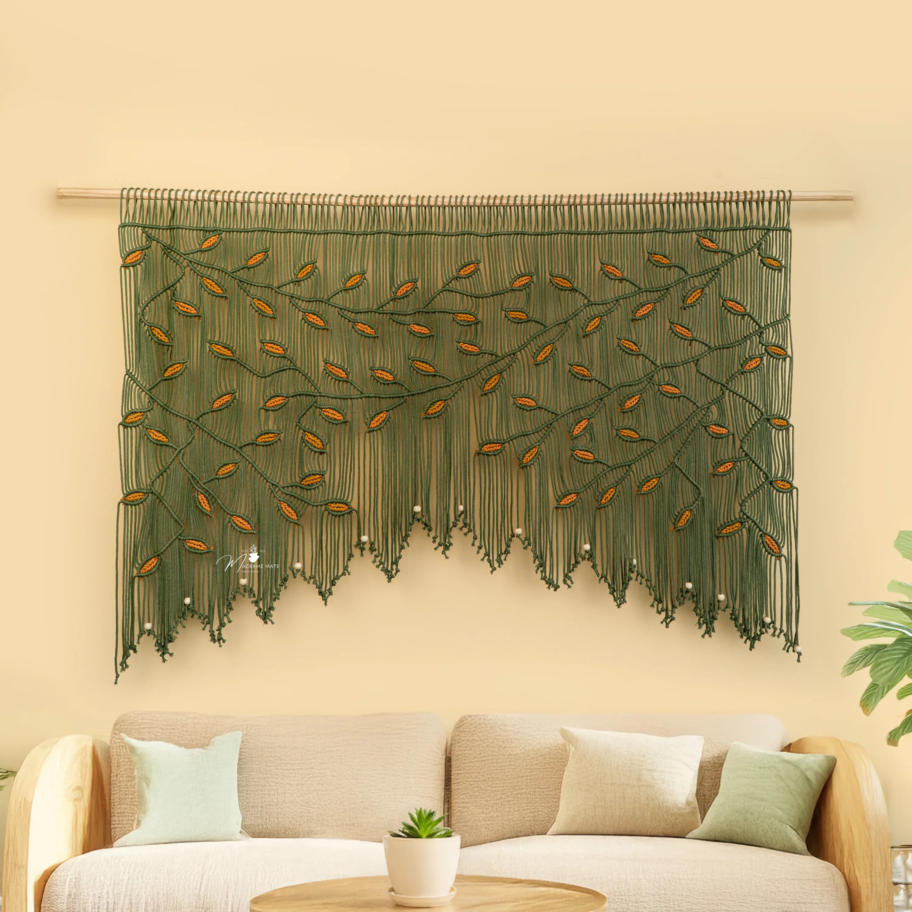 Decorative wall hanging with leaf pattern above a beige sofa on a light yellow wall.