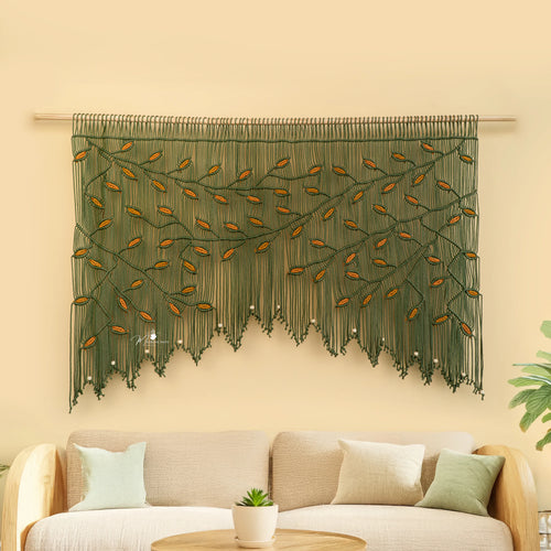 Decorative wall hanging with leaf pattern above a beige sofa on a light yellow wall.
