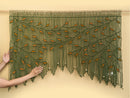 Textile art piece with green and orange pattern on a beige background