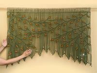 Textile art piece with green and orange pattern on a beige background