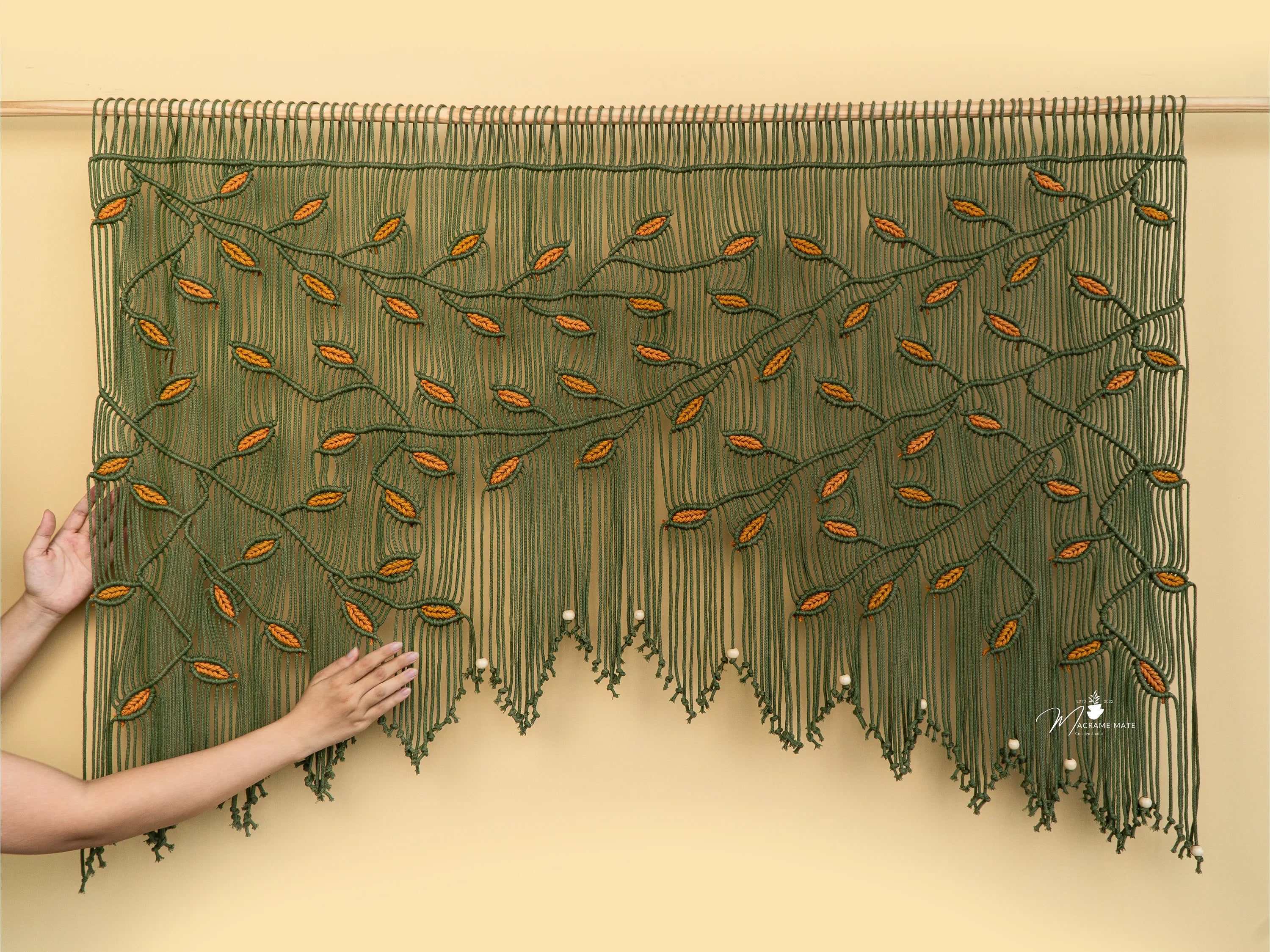 Textile art piece with green and orange pattern on a beige background