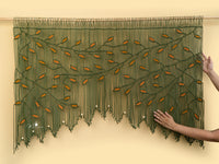 Decorative green and orange beaded curtain on a beige wall.