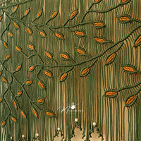 Close-up of embroidered fabric with green and orange pattern, featuring a brand logo.