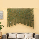 Decorative green wall hanging with leaf pattern on a beige wall above a gray sofa.
