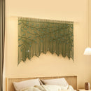 Decorative string art with green leaves on a beige wall above a bed.