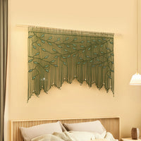 Decorative string art with green leaves on a beige wall above a bed.