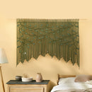 Decorative green wall hanging with leaf pattern on a beige wall above a bed.