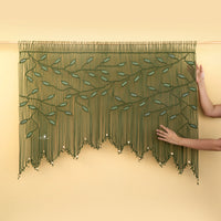 Decorative green beaded curtain with leaf patterns on a beige wall.