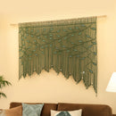 Decorative green wall hanging with leaf pattern on a beige wall above a brown sofa.