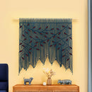 Decorative wall hanging with blue and red pattern on a yellow wall above a wooden console table.