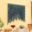 Decorative string wall hanging with red accents on a yellow wall above a wooden console table.