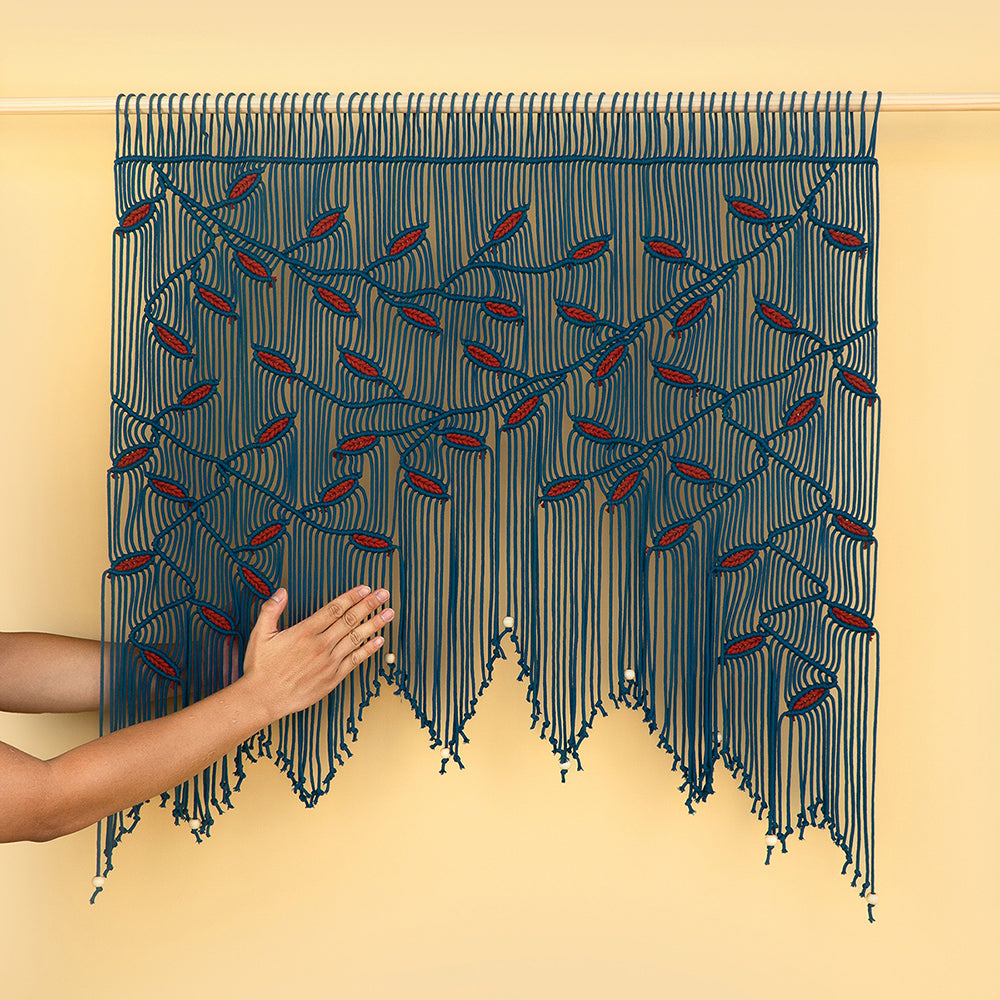 Handmade macrame wall hanging with blue and red pattern on a beige background