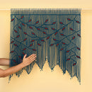 Handmade macrame wall hanging with blue and red pattern on a beige background
