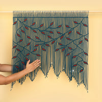 Handmade macrame wall hanging with blue and red pattern on a beige background