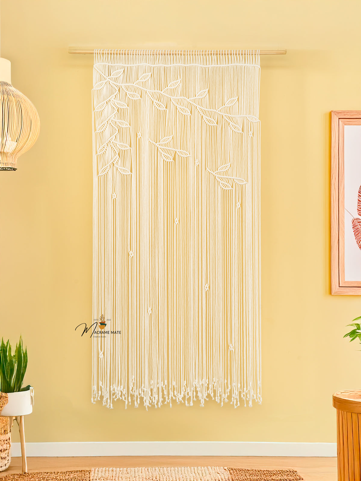 String art wall decoration on a yellow wall with a framed picture and plants.