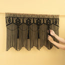 Black macrame curtain with geometric patterns on a beige background