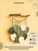Decorative wall hanging with leaves on a branch against a beige background