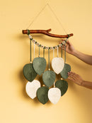 Handmade wall hanging with leaf-shaped fabric pieces on a yellow background