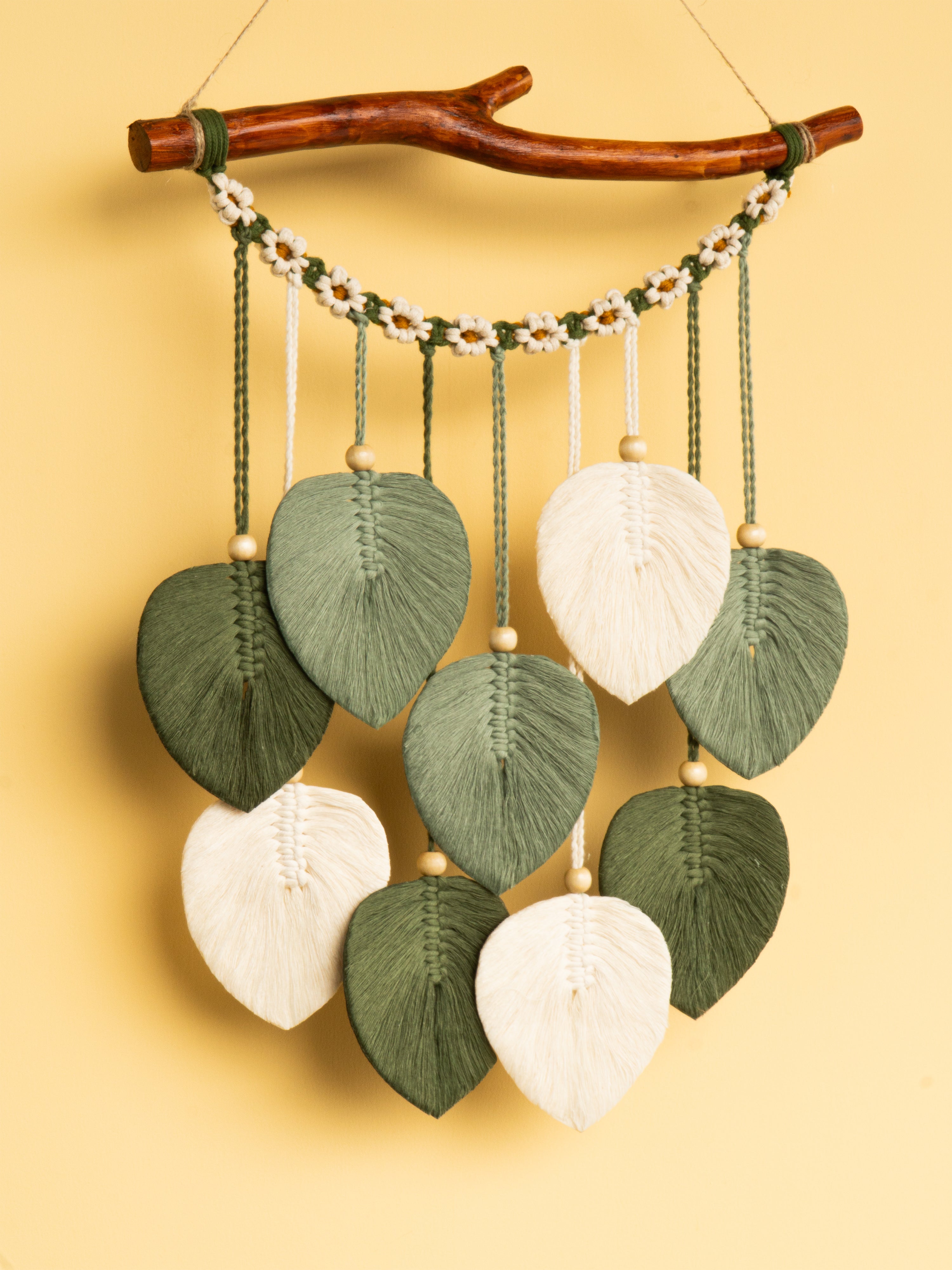 Decorative wall hanging with leaf-shaped beads on a yellow background