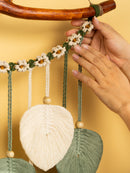 Handmade macrame wall hanging with floral and leaf designs on a yellow background