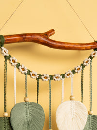 Decorative wall hanging with yarn and wooden elements on a yellow background