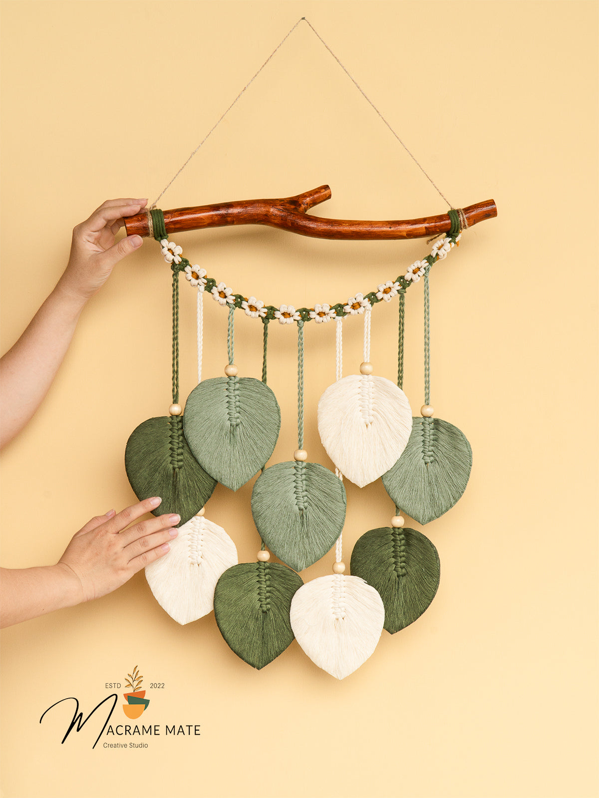 Decorative wall hanging with leaf-shaped beads on a beige background, featuring the brand 'Macrame Mate'.