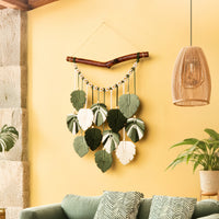 Decorative wall hanging with leaf-like elements on a yellow wall in a living room.