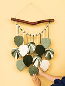 Handmade wall hanging with knitted leaf shapes on a yellow background