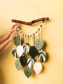 Handmade wall hanging with leaf-shaped fabric pieces on a yellow background