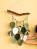 Handmade wall hanging with leaf-like decorations on a yellow background