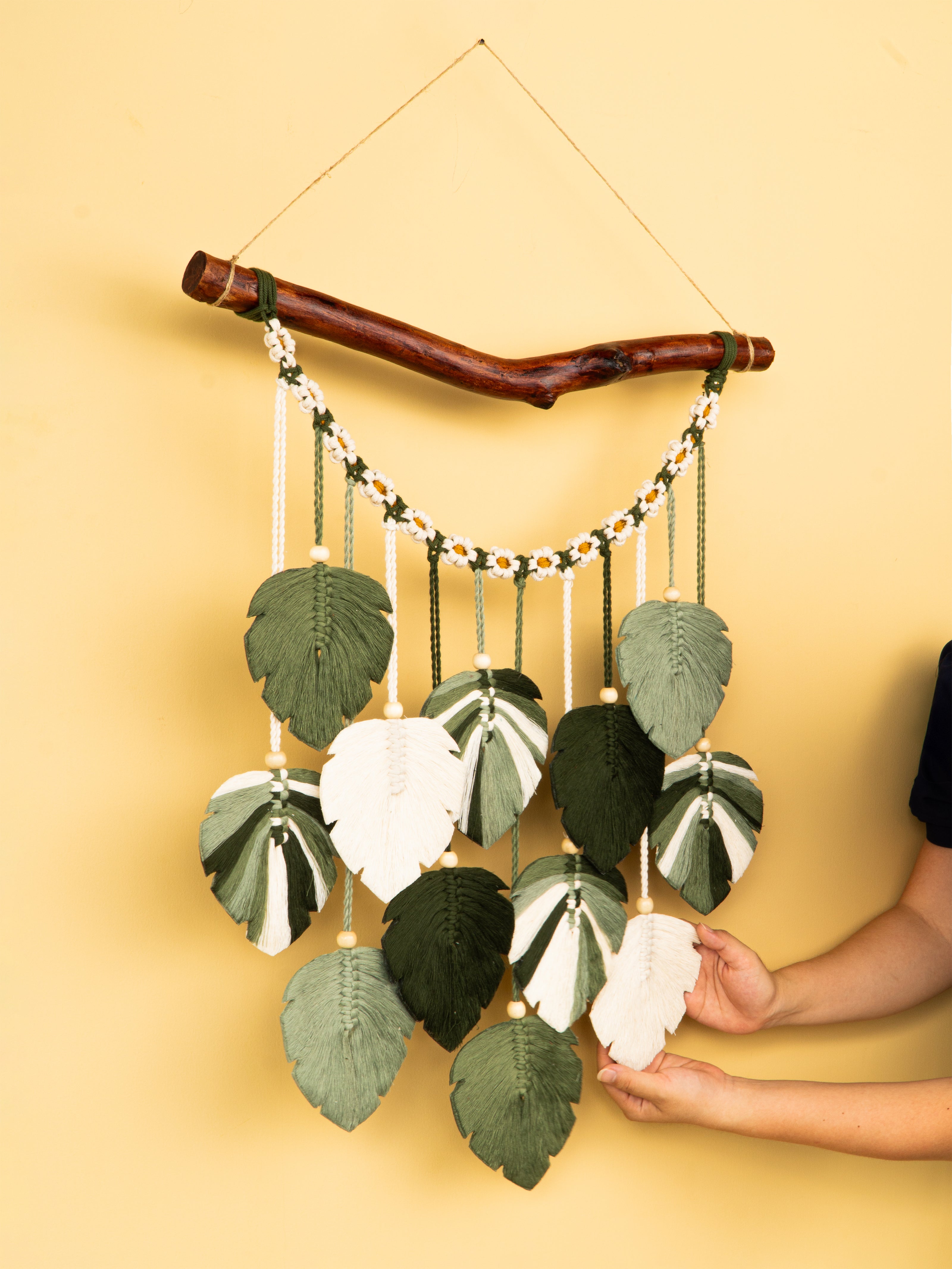Handmade wall hanging with leaf-like decorations on a yellow background
