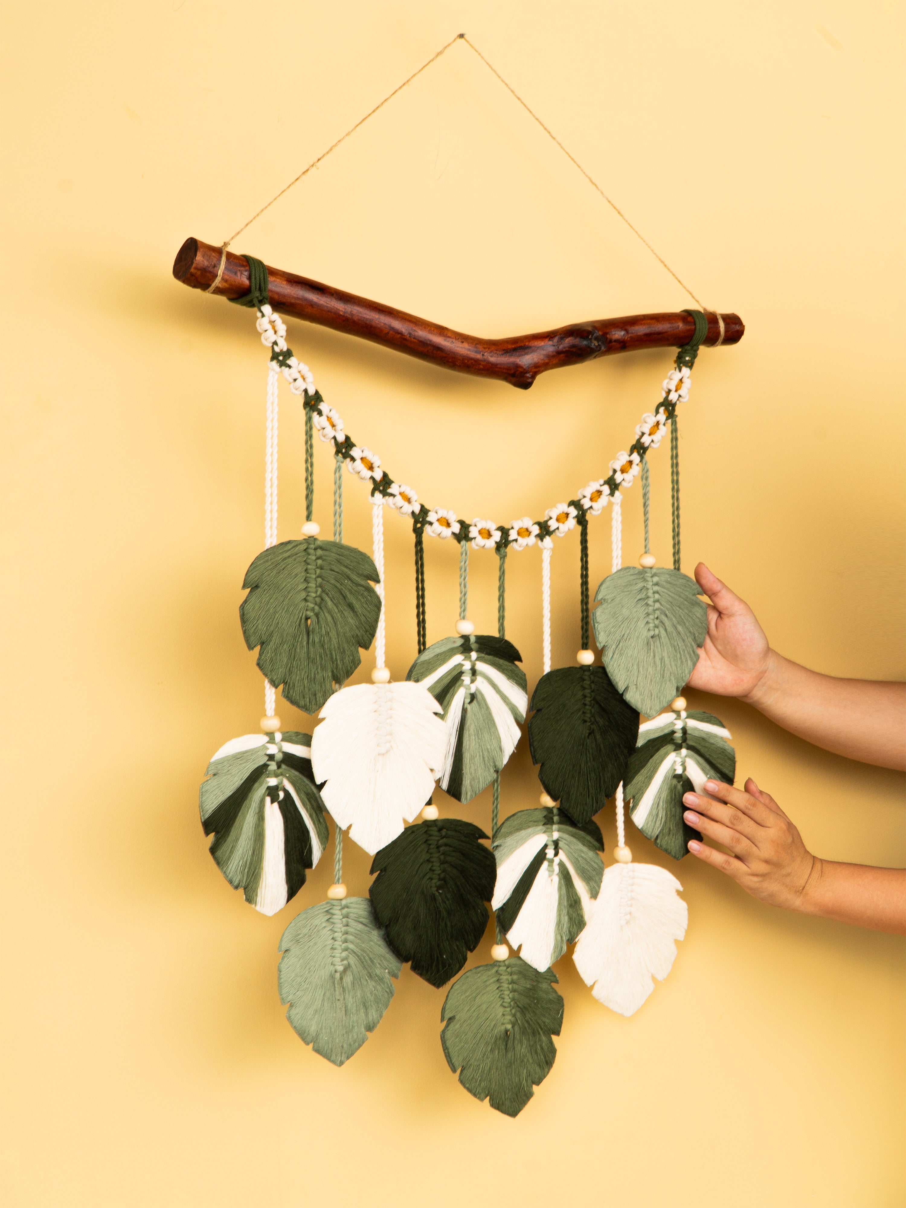 Handmade wall hanging with leaf patterns on a yellow background