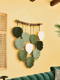 Decorative wall hanging with leaf patterns on a yellow wall.