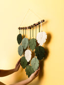 Handmade leaf-shaped wall hanging with green and white leaves on a yellow background